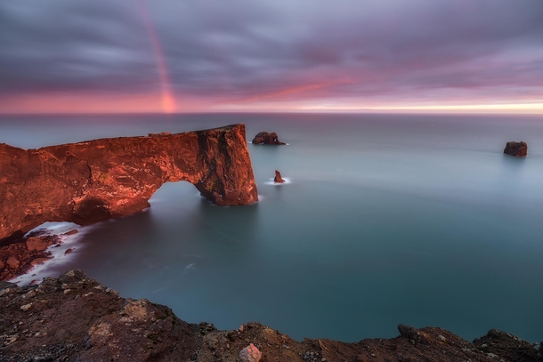 Rainbow over a sea arch at sunset in Iceland 