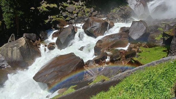 Rainbow over a stream at the bottom of a waterfall in Yosemite 