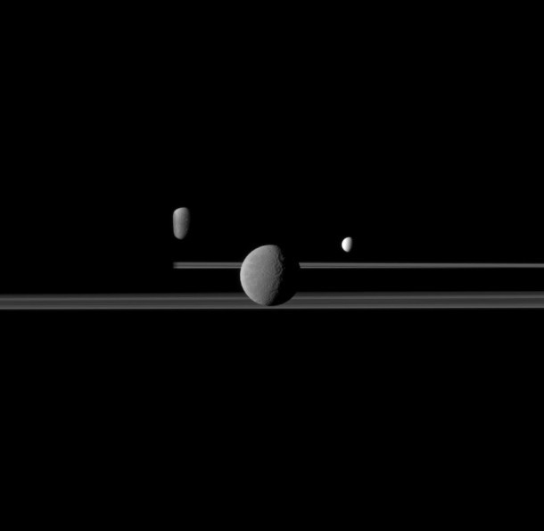 Rhea Enceladus and Dione join the rings of a darkened Saturn horizon 