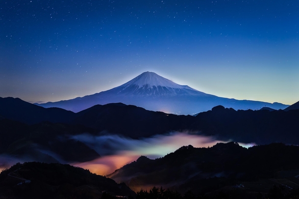 Sacred Mountain - Mount Fuji among clouds lit up by lights below  by Yuga Kurita x-post rJapanPics