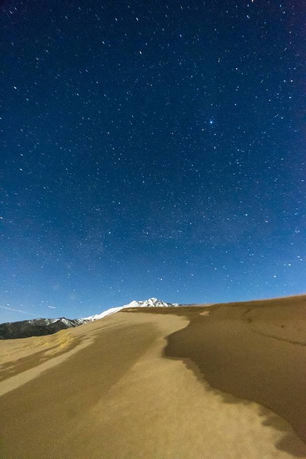 Sand and snow capped mountains under the stars at Great Sand Dunes National Park Colorado 