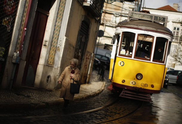 Street scene A woman walks near a tram at the Alfama neighborhood in Lisbon Portugal