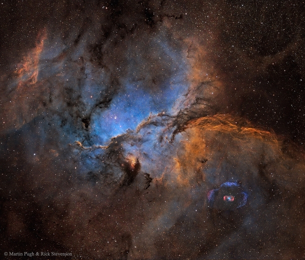 Swirling clouds of glowing gas in the giant star forming region NGC  in the lower right is the rare emission nebula NGC   By Martin Pugh and Rick Stevenson