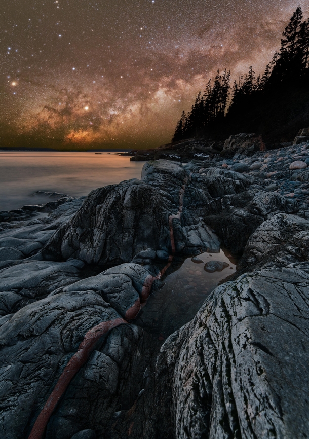 The Milky Way rises over copper leading lines on the shore of Acadia National Park 