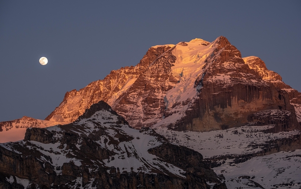 The super moon rises during sunset next to the m  ft high Jungfrau in the Swiss Alps 