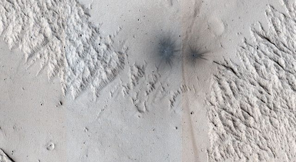 This image shows the land near Mangala Valles on Mars At the bottom of the image there are two black dots which are recent impact craters This image comes from Nasa