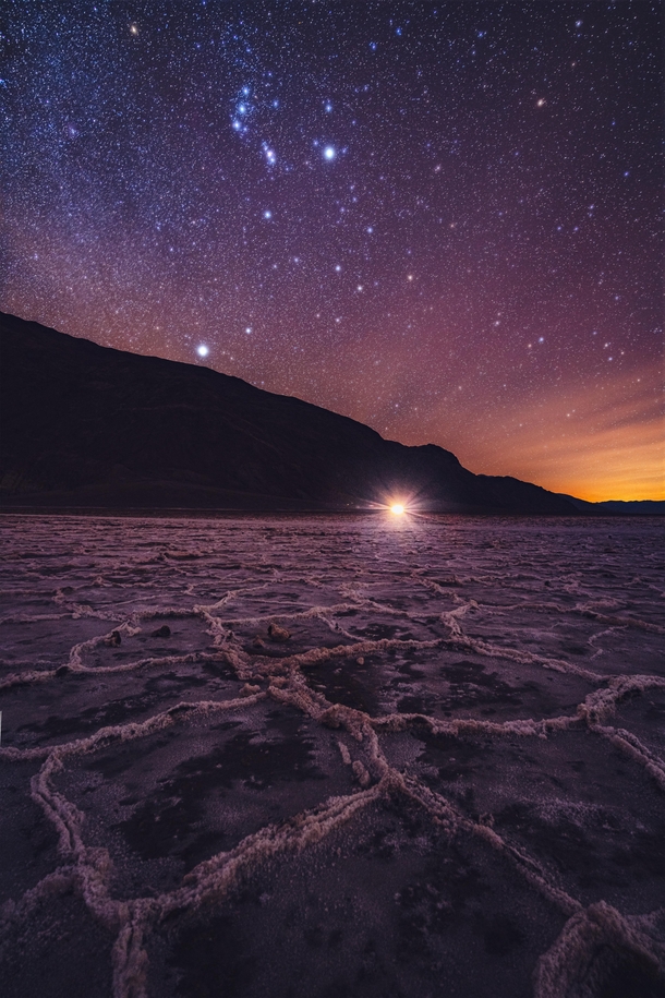 This is Badwater Basin in Death Valley As Orion rises overhead the distant glow from Las Vegas illuminates the salt flats 