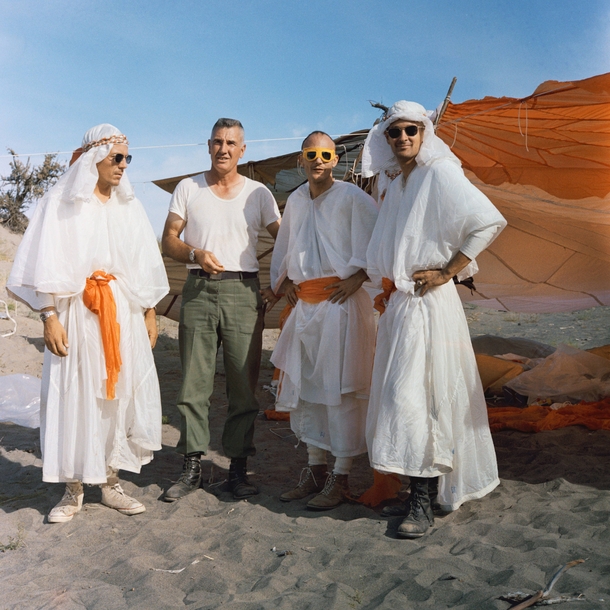 Three Apollo astronauts in survival training clothed with parachute fabric  