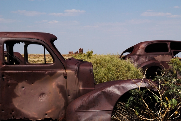 Vintage rusted cars and a crumbling stone building 