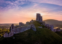 A drone shot of Corfe Castle soon after sunrise The castle was built in the nd half of the th Century and is located in Dorset near the South Coast of England