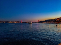 A ferry crosses the bosphorus in stanbul in front of the Bosphorus Bridge at sunset 