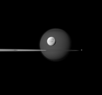 A quartet of Saturns moons Titan Dione Pandora and Pan surround and are embedded within the planets rings in this Cassini composition 
