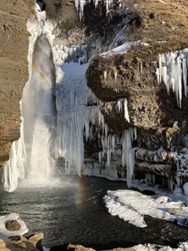 A rainbow in front of a frozen Gluggafoss in Iceland 