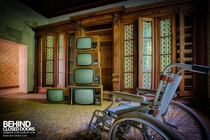 A wheel chair in front of a pile of old TVs in an abandoned hospital in Germany full set in comments 