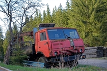 Abandoned and overgrown Kamaz logging truck near an old sawmill 