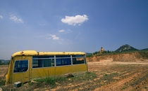 Abandoned Chinese school bus by a big golden statue of Lao Tzu From another angle