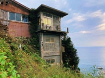 Abandoned cliffside home in Japan Notice the vines growing inside the windows 