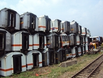 Abandoned Indonesian commuter trains stacked high on a field near Purwakarta Station Photo by cc 
