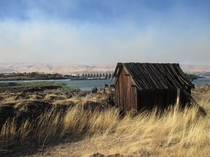 Aging wooden shack near The Dalles dam Oregon backed by the haze of a nearby wildfire 
