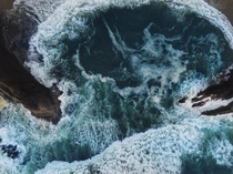 An ocean wave pouring into a beach cove from above 