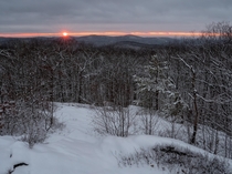 An orange beam seems to appear in the sky as the setting sun shines through the gap between the cloud cover and the horizon Taken following a recent snow storm in Western Massachusetts 