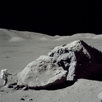 Apollo  astronaut Harrison Schmitt standing next to a boulder during the third EVA 