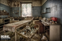 Archaic medical items on a trolley next to an examination bed in decaying urology surgery 