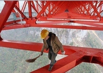 At more than a  feet above the ground daredevil workers put the finishing touches to the Anzhaite long-span suspension bridge the worlds highest and longest suspension bridge in Jishou China before it opens to the public