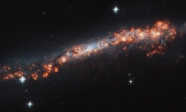 Believe it or not this long glowing streak speckled with bright blisters and pockets of material is a spiral galaxy like our Milky Way But how could that be It turns out that we see this galaxy named NGC  oriented directly edge-on to us from our vantage p