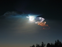 Bright light from a setting Sun and pale glow from a rising Moon both contribute to this stunning picture of a rocket exhaust trail twisting and drifting in the evening sky Launched from Vandenberg Air Force Base it carried its test payload thousands of m