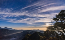 Caught the last glimpse of the stars and moonlight before the sun dominates the scene with volcanic smoke circling around the foreground View point of Mt Bromo in Surabaya Indonesia 
