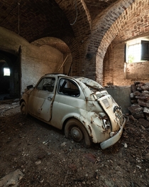 Dented old Fiat  inside an abandoned Italian country house 