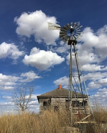 Farmstead in very rural Nebraska just north of the Kansas state line We were on a road trip to Colorado and when we passed this beauty I just had to pull over The combination of house windmill dead trees and those beautiful puffy clouds was truly amazing 