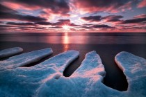Fingers of ice reaching towards the sun setting over the tranquil shores of Lake Michigan 