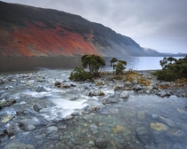 Gentle cascading beck pours into the deep gloom of Wastwater Wasdale Lake District England 