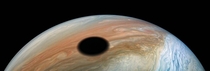 Jupiters volcanic companion Io casting a shadow above Jupiters swirling storms--Enhanced color image made from images captured by the Juno spacecraft