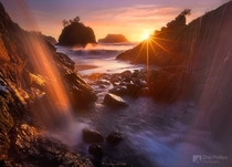 Looking out on the Oregon coastline from behind a waterfall  by Chip Phillips