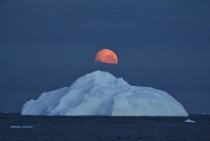 Midnight moon floating over an iceberg 