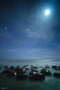Moon and Orion setting over alien-looking rocks on the northern California coast 
