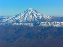 Mount Damavand the white giant rising from the wrinkled earth of the Alborz mountains in Iran 