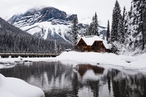 Small wooden house covered with snow near the emerald lake in Canada