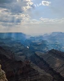 Sun rays peaking from behind the clouds with a light haze in the air from wildfires Grand Canyon National Park AZ