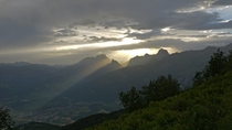 Sun rising over mountains through clouds Monthey Switzerland 