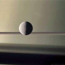 Thats Rhea Saturns second-largest moon and Epimetheus the smaller moon to the right against a backdrop of Saturn its rings and ring shadows