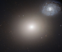 The bright core and outer reaches of giant elliptical galaxy M NGC  loom large at the upper left of this image Some  million light-years away and  light-years across M is one of the largest galaxies in the nearby Virgo Cluster 