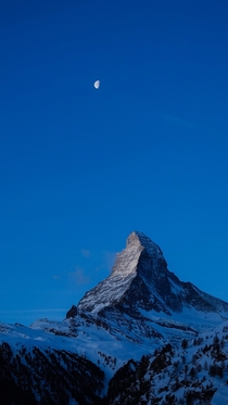 The moon rises over the Matterhorn in Zermatt Switzerland 