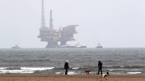 The Shell Brent Delta platform is brought inshore on a barge to be broken up 