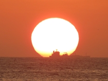 The sun setting with a ship ahead of it