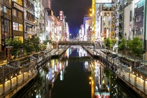 Waterway lined with brightened buildings on each side in Osaka Japan by uIamthetophergopher x-post rtravel 